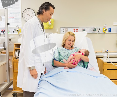 Image of Mother And Doctor Looking At Newborn Baby Girl In Hospital