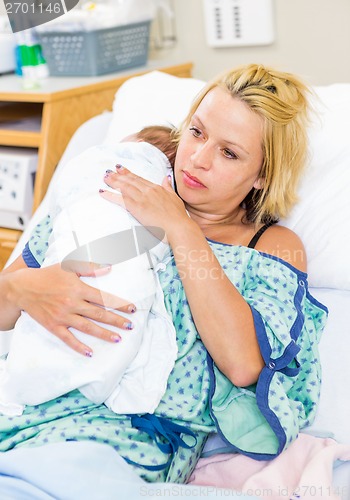 Image of Woman With Baby Resting On Her Shoulder In Hospital