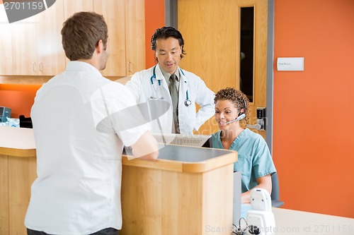 Image of Doctor And Nurse Working While Man Standing In Hospital