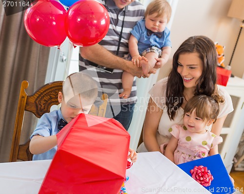 Image of Family Looking At Birthday Boy Opening Gift Box