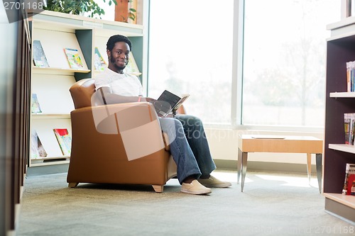 Image of Young Student Reading Book In Library