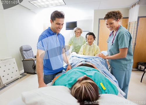 Image of Happy Medical Team And Husband Looking At Pregnant Woman