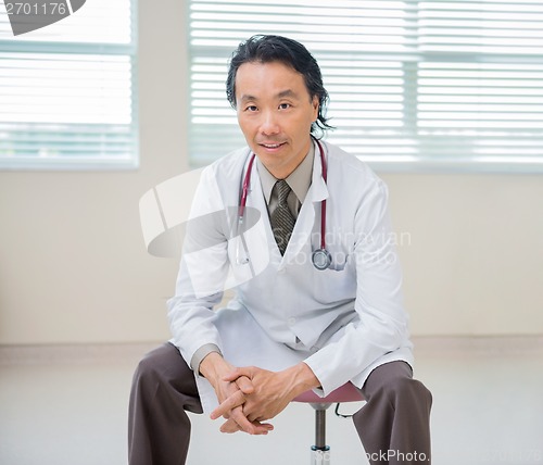 Image of Doctor Sitting At Hospital Room With Patient In Background