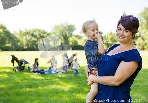 Image of Happy Mother Carrying Son In Park