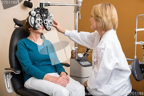Image of Optician Using Phoropter To Examine Woman's Eyes