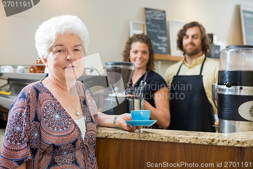 Image of Woman Holding Coffee Cup With Workers At Counter