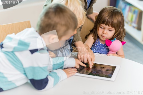 Image of Children Using Digital Tablet In School Library