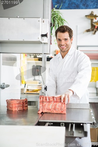 Image of Portrait Of Butcher Slicing Meat On Bandsaw