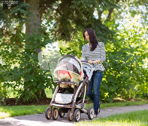 Image of Woman Pushing Baby Carriage In Park