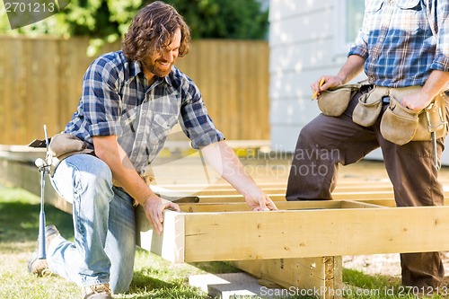 Image of Workers Working On Wooden Frame At Construction Site