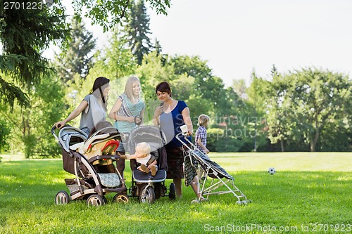 Image of Mothers With Baby Strollers Reading Text Message