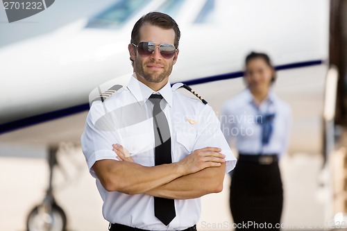 Image of Pilot With Arms Crossed Standing Against Stewardess And Private