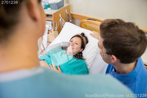 Image of Pregnant Woman Looking At Nurse By Husband In Hospital