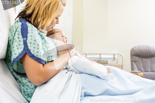 Image of Woman Looking At Newborn Babygirl On Hospital Bed