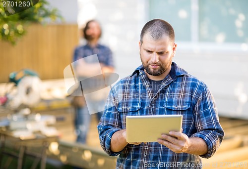 Image of Manual Worker Using Digital Tablet With Coworker Standing In Bac