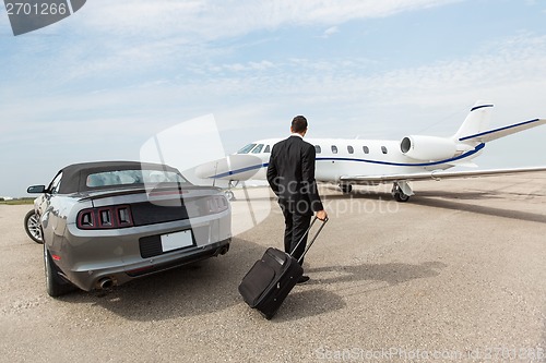 Image of Businessman Standing By Car And Private Jet At Terminal