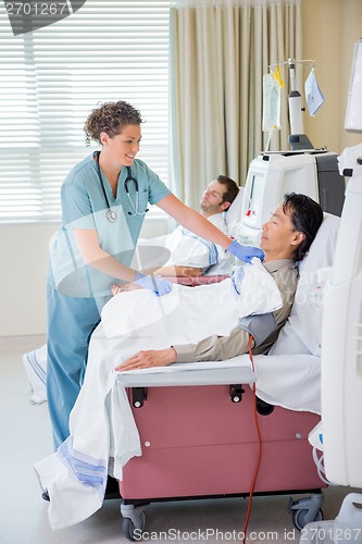 Image of Nurse Covering Patient Undergoing Renal Dialysis With Blanket