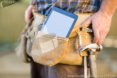 Image of Digital Tablet And Hammer In Carpenter's Tool Belt