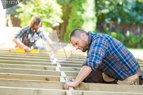 Image of Carpenter Using Drill On Wood At Site