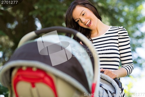 Image of Woman Looking Into Baby Carriage In Park