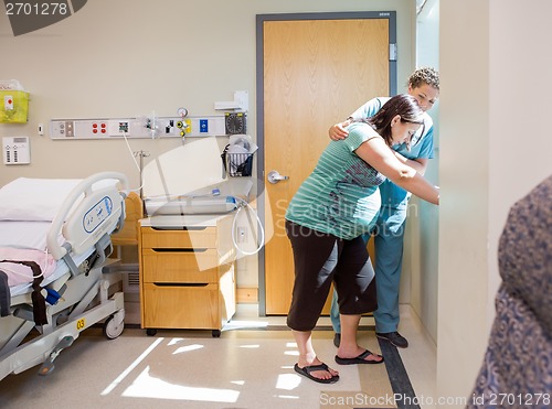 Image of Nurse Comforting Tensed Pregnant At Window In Hospital Room