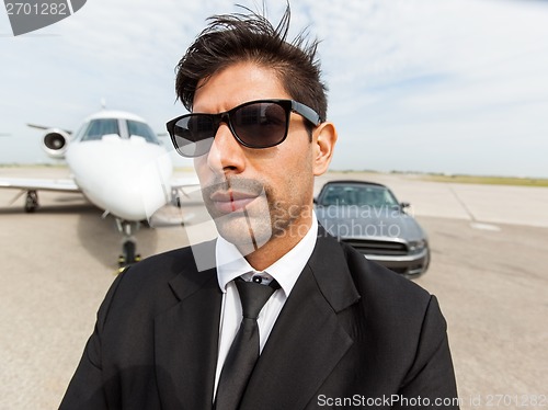 Image of Confident Businessman In Front Of Car And Private Jet