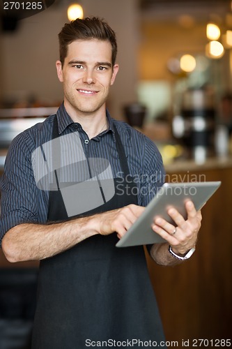 Image of Male Owner Holding Digital Tablet In Cafeteria