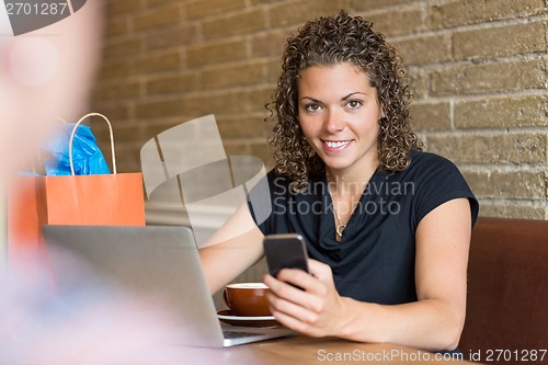 Image of Portrait Of Woman Holding Mobilephone In Cafe