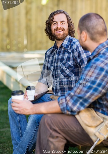 Image of Happy Worker Holding Disposable Cup While Sitting With Coworker