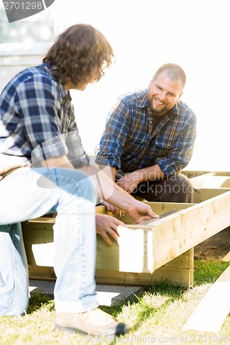 Image of Carpenter Measuring Wooden Frame While Coworker Looking At It