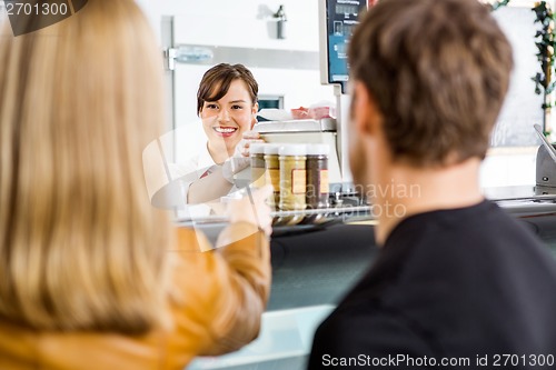 Image of Saleswoman Attending Customers At Butcher's Shop