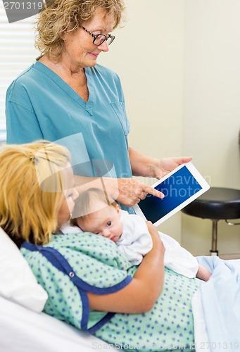 Image of Mature Nurse Explaining Reports On Tablet To Woman With Babygirl