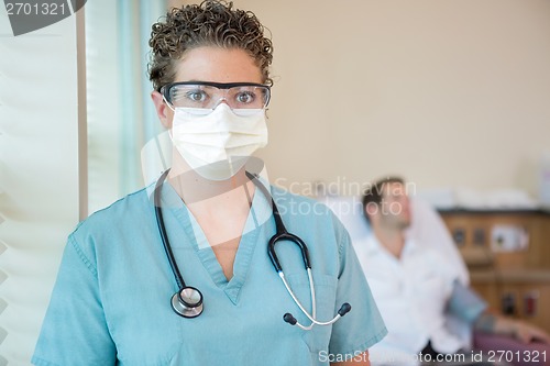 Image of Nurse In Protective Clothing With Patient In Background