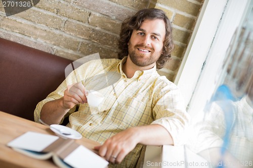 Image of Man With Coffee Cup And Book In Cafe