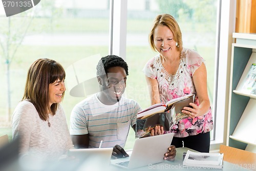 Image of Happy Librarian Assisting Students In Library