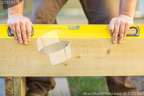 Image of Carpenter's Hands Using Spirit Level On Wood