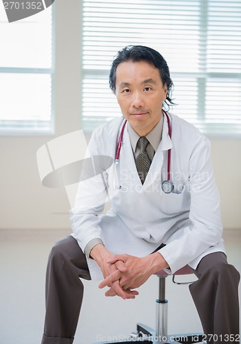 Image of Doctor With Hands Clasped Sitting In Hospital Room