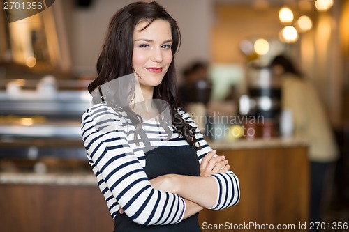 Image of Pretty Waitress Standing Arms Crossed In Cafeteria