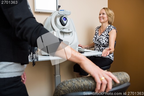 Image of Happy Optician Asking Patient To Sit In Store