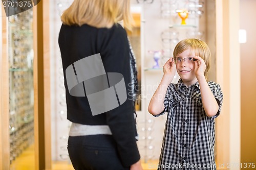 Image of Boy Looking At Mother While Trying On Spectacles In Shop