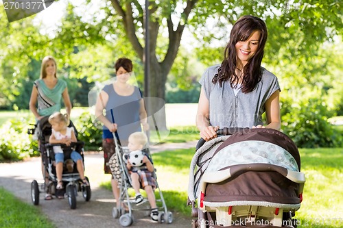 Image of Mother Looking At Baby In Stroller At Park