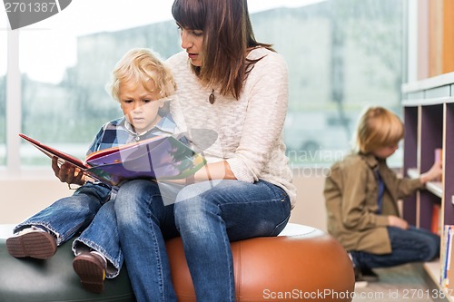 Image of Teacher With Boy Reading Book In Library