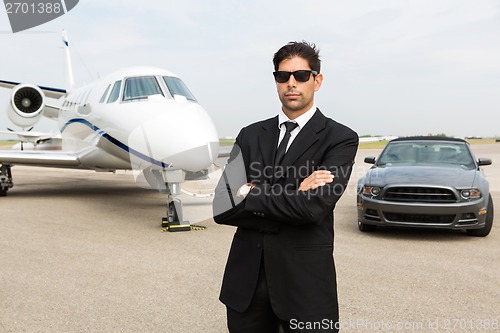 Image of Businessman Standing In Front Of Car And Private Jet