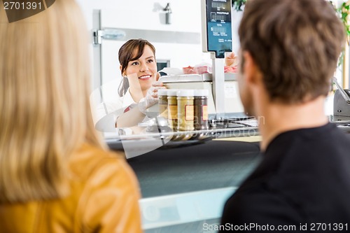 Image of Saleswoman Looking At Customers In Butcher's Shop