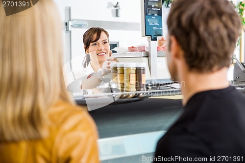 Image of Saleswoman Looking At Customers In Butcher's Shop