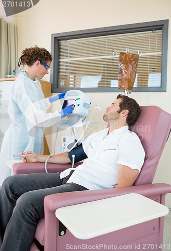 Image of Patient Looking At Nurse Operating Heartbeat Machine