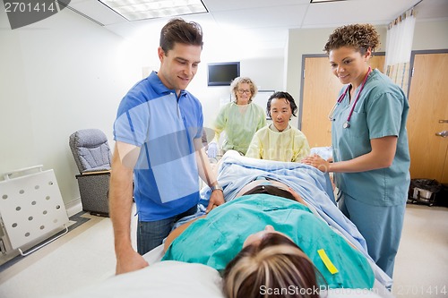 Image of Medical Team And Husband Looking At Pregnant Woman