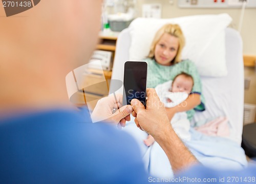 Image of Man Photographing Woman And Babygirl Through Cell Phone