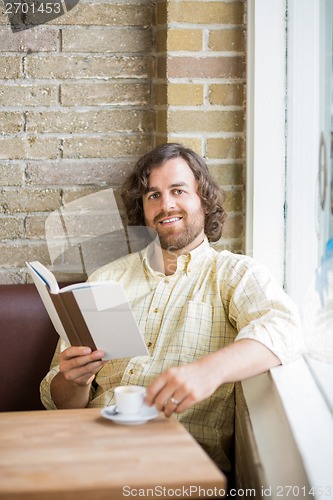 Image of Man With Book And Coffee Cup Sitting In Cafeteria