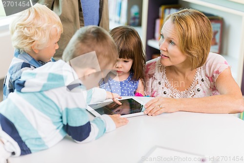 Image of Teacher With Students Using Digital Tablet In Library